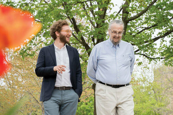 Professor Nuno Moniz and Professor Don Howard walk side by side on campus, talking and smiling